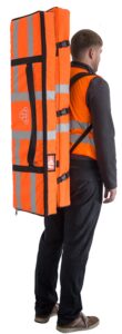 Mitarbeiter trägt zwei orange-farbene Taschen, in denen mobile Spannungsprüfer transportiert werden
