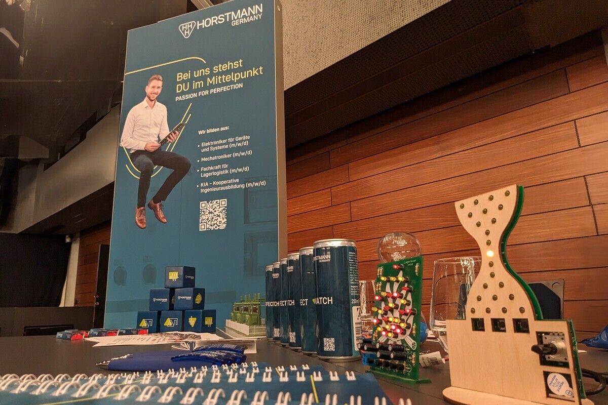 Im Vordergrund sind Werbemittel und ein LED-Steckspiel. Im Hintergrund sieht man eine leuchtende Box mit einem jungen Mitarbeiter.