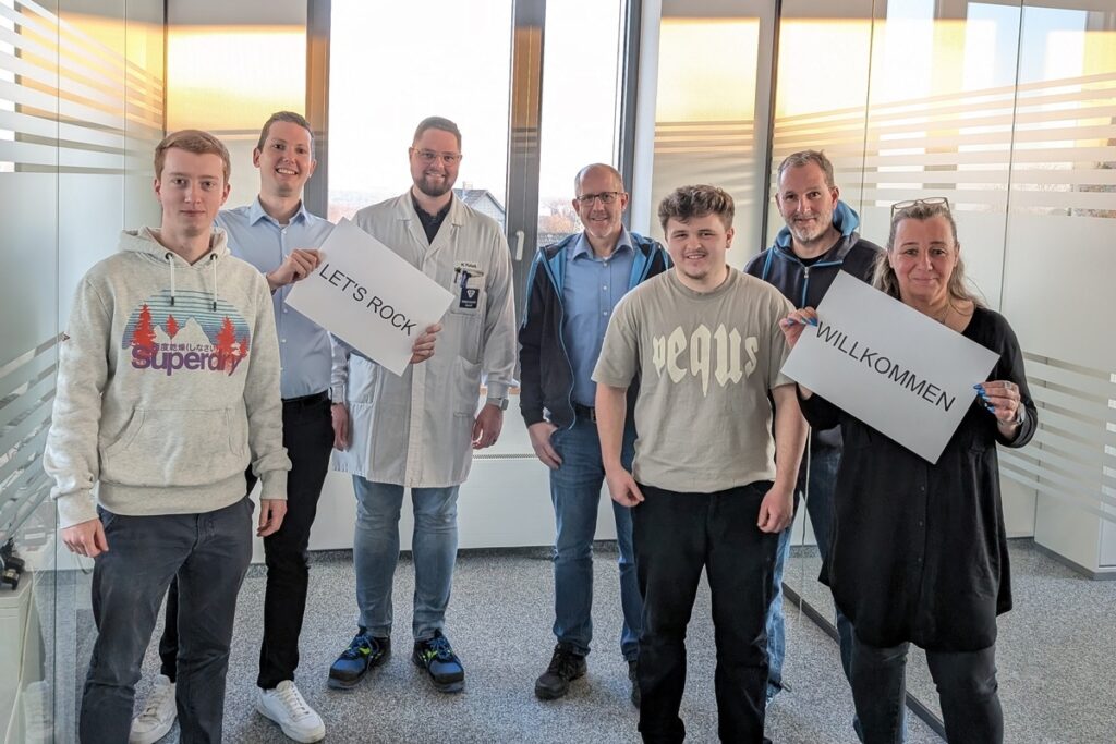 Zwei Auszubildende haben die Abschlussprüfung bestanden und werden von Ihren neuen Team Kollegen gefeiert.