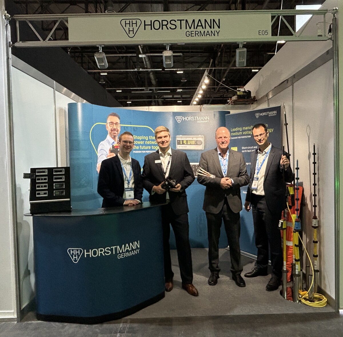 Vier Männer in Anzügen vor einem mobilen Horstmann Messestand