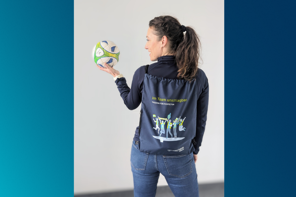 Mitarbeiterin hält einen Fußball in der Hand und trägt auf dem Rücken einen Rucksack der Firma Horstmann