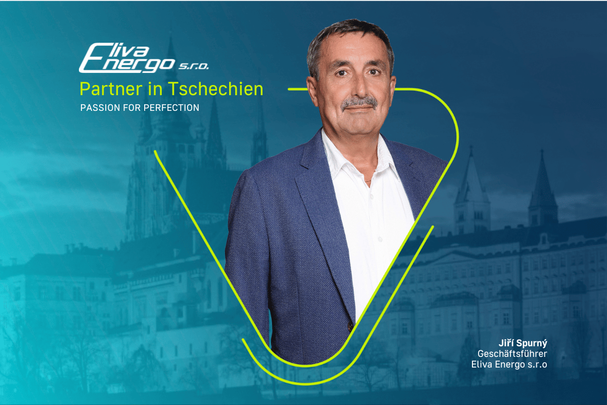 Älterer Partner mit blauem Sakko und weißen Hemd in Portraitaufnahme. Im Hintergrund ist ein tschechisches Stadtbild