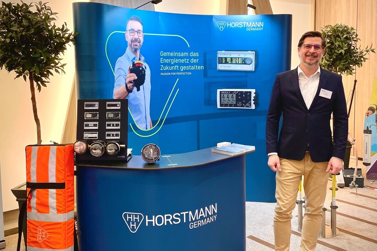 Mitarbeiter in Businesskleidung steht auf einem Horstmann-Messestand und präsentiert die Produkte