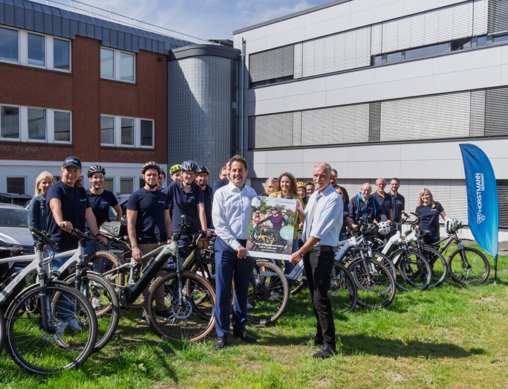Eine Gruppe von Menschen mit Fahrrad, 2 Männer im Vordergrund, mit einem Plakat in der Hand