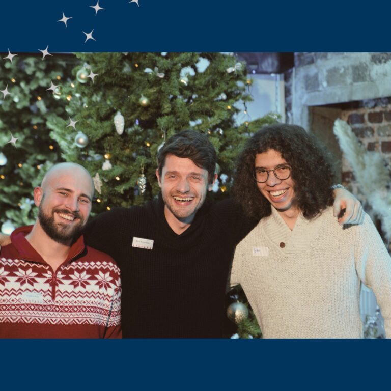 Drei junge Kollegen von Horstmann stehen bei der Weihnachtsfeier zusammen und lachen in die Kamera